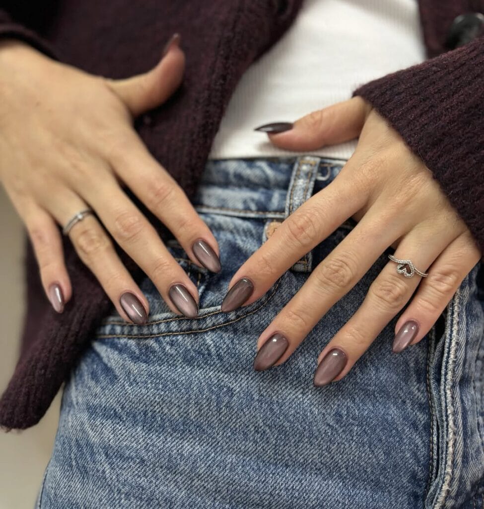 Smoky taupe autumn nails with a reflective silver cat-eye stripe and glossy almond shape.