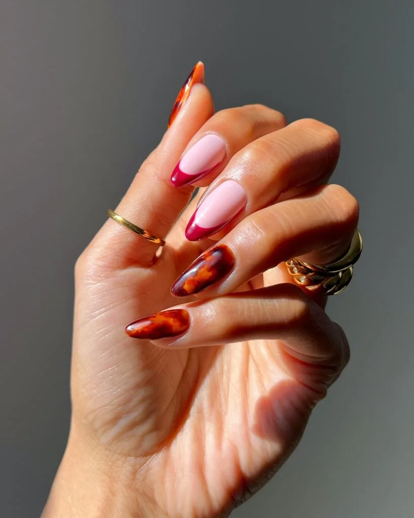 Early fall nails with burgundy French tips and translucent amber tortoiseshell accent nails.