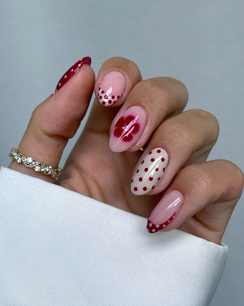 Fall polka dot nails with red and white French tips, a milky dotted accent, and a red flower on pink.
