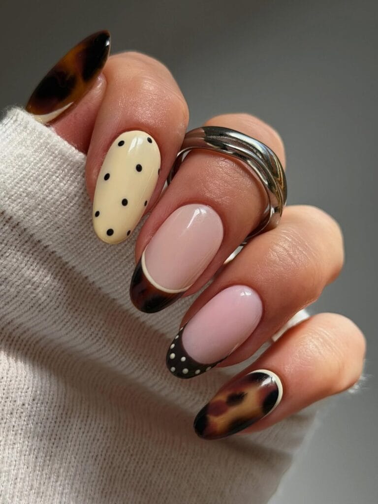Tortoiseshell fall nails with cream polka dots, pink bases, and dark dotted French tips.
