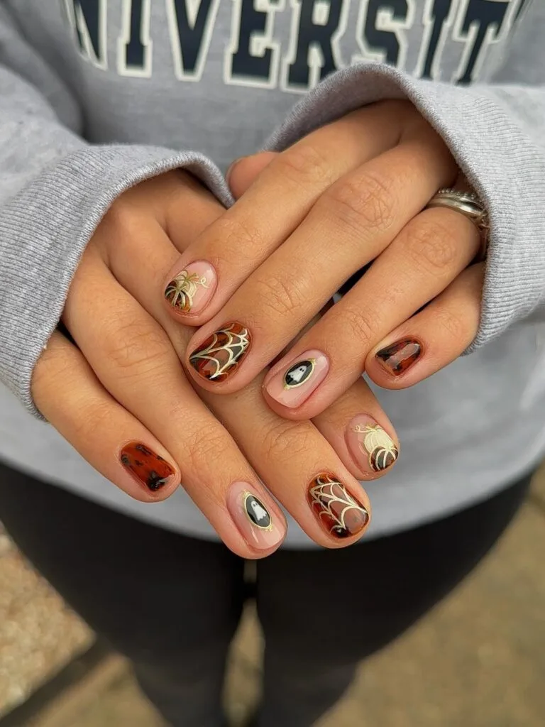 short Halloween nails with tortoiseshell polish, spiderweb art, ghost accents, and pumpkin details