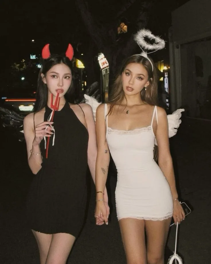 Best friend Halloween costumes with a black devil dress, red horns, and a white angel dress with wings and halo.