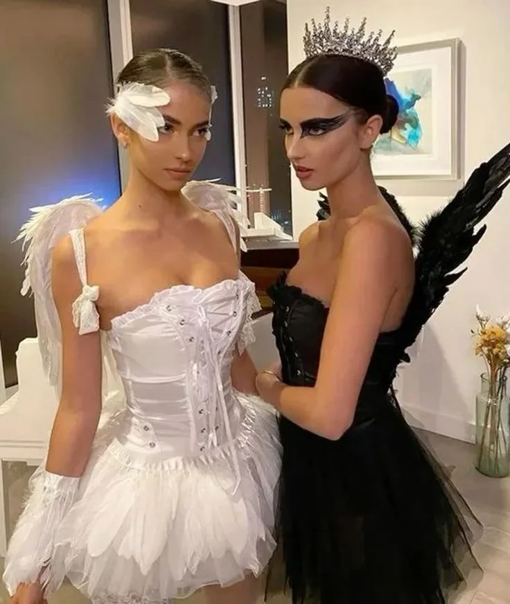 Black and white swan Halloween costumes for best friends with corsets, tulle skirts, feathered wings, and dramatic makeup.