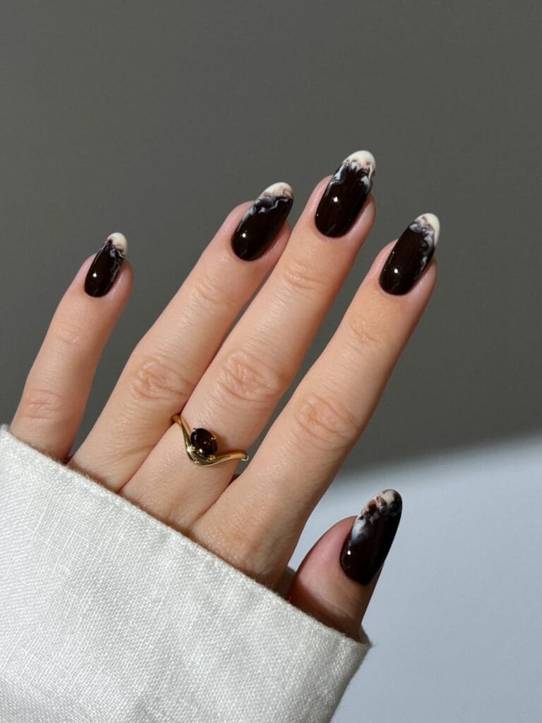 Glossy dark brown October nails with milky white smoke tips on almond shapes.
