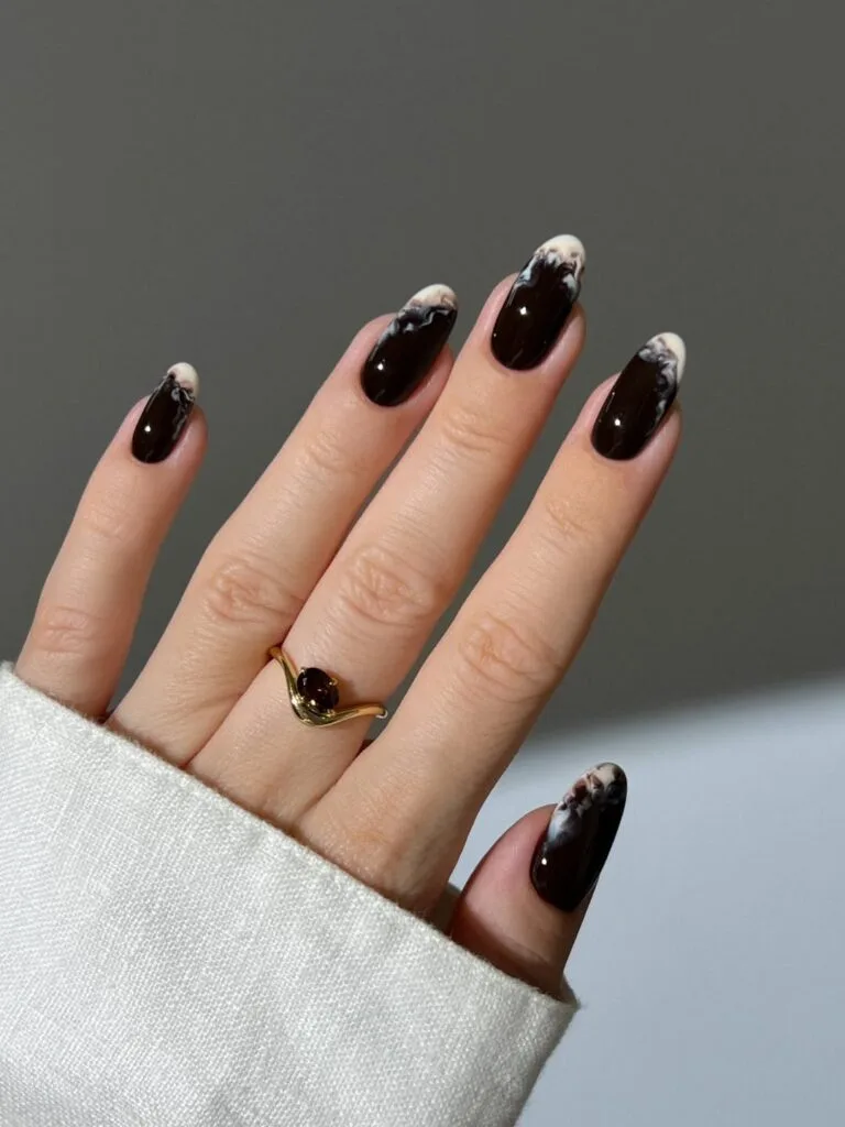 Glossy dark brown October nails with milky white smoke tips on almond shapes.
