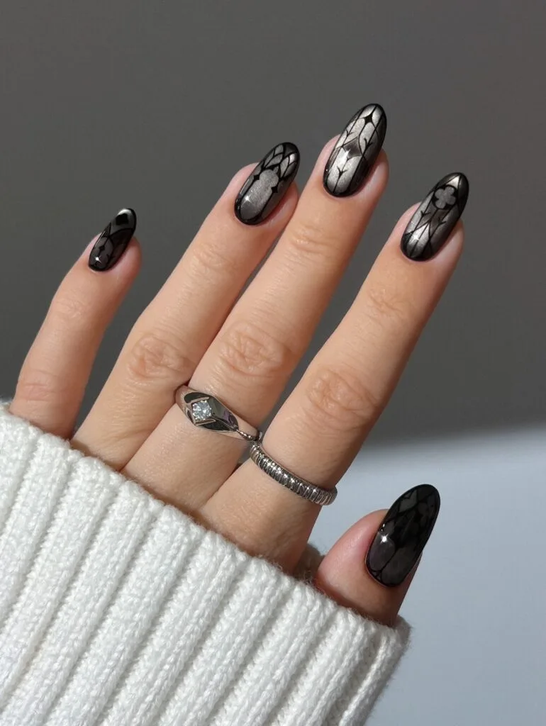 Silver and black witchy nails with fine Gothic window outlines and dark borders on oval shapes.