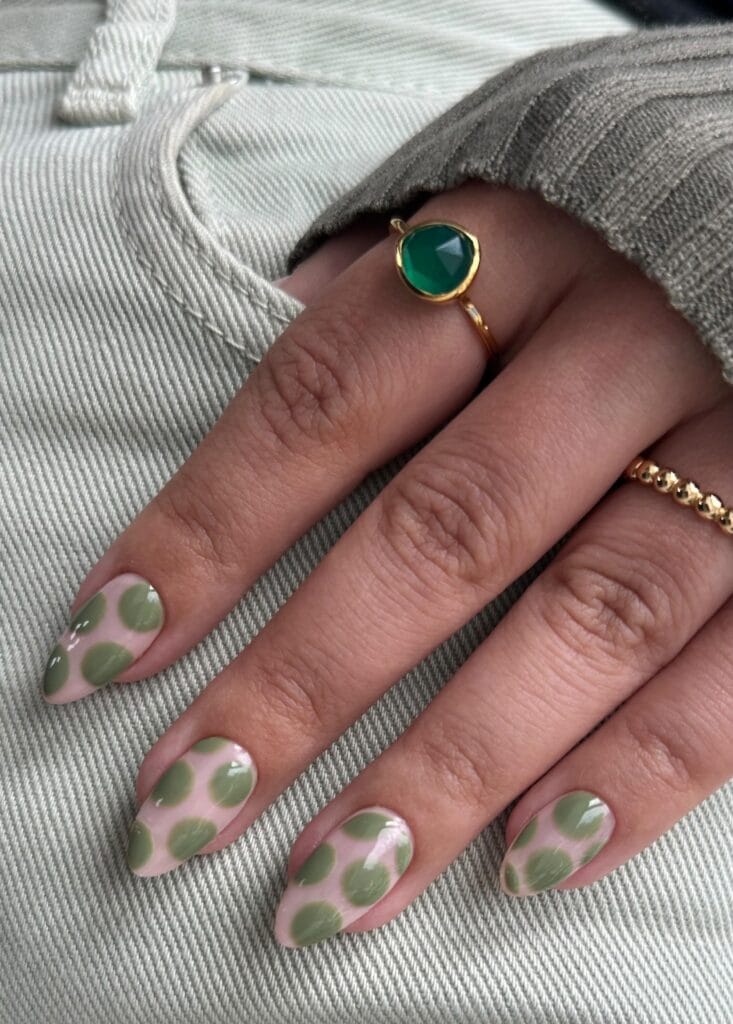 Almond fall polka dot nails with a pale pink base and oversized sage green circles.

