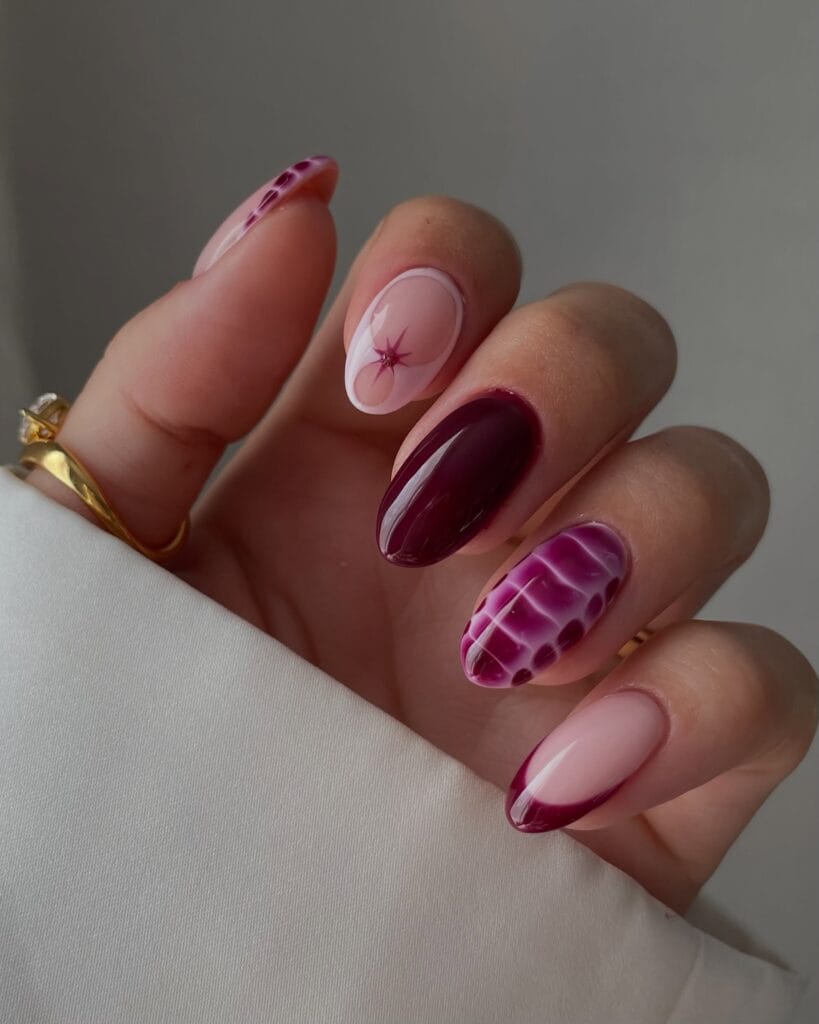 Berry pink autumn nails with burgundy polish, croc-pattern nail art, curved tips, and a tiny starburst.
