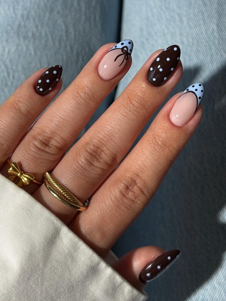Chocolate fall polka dot nails with blue dots, pale blue dotted French tips, and a fine brown bow.
