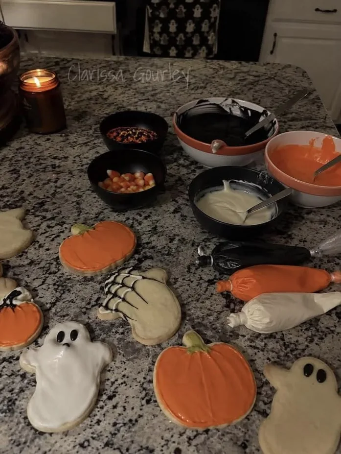 Halloween cookie decorating setup with pumpkin, ghost, and skeleton cookies, icing, sprinkles, and piping bags
