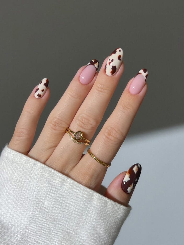 Fall nail designs with brown and white cow print French tips over a glossy pink base.
