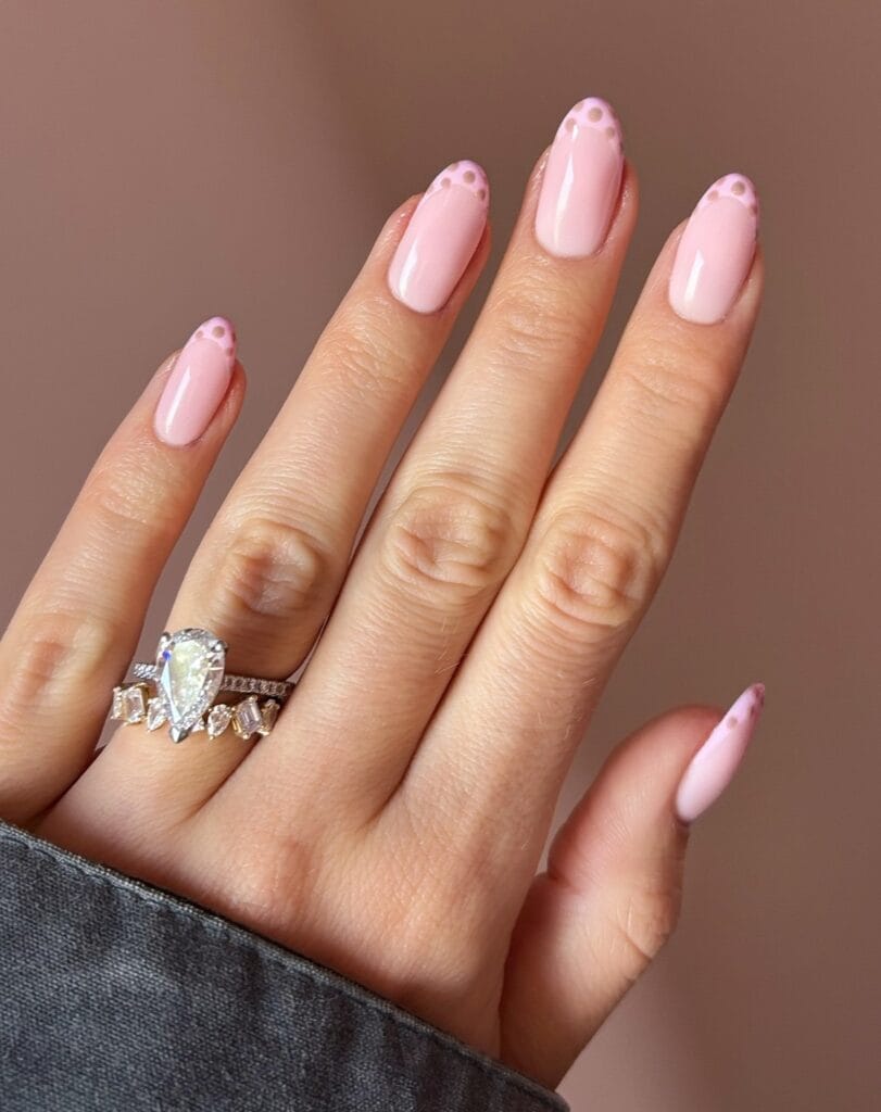 Glossy pink almond autumn nails with pale pink French tips and small taupe polka dots.
