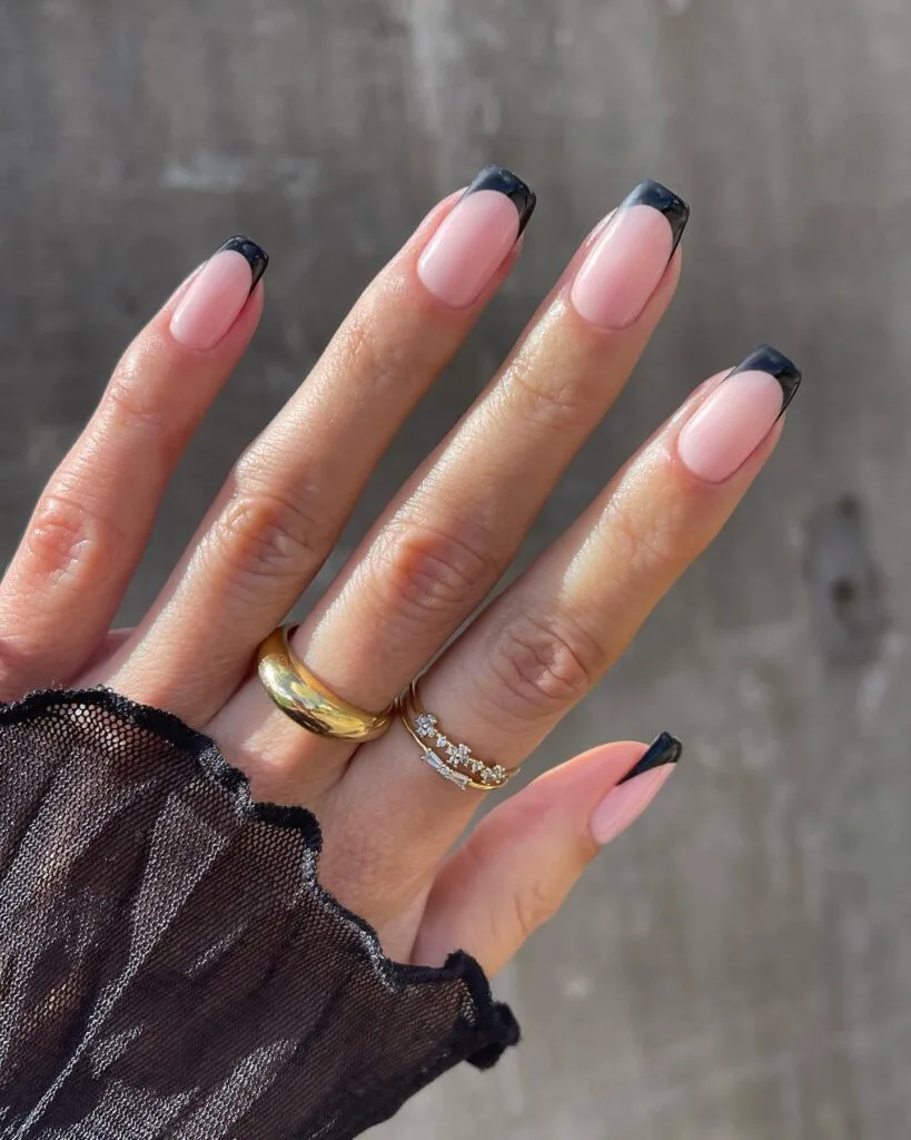 Square witchy nails with glossy pale pink bases and crisp black French tips.