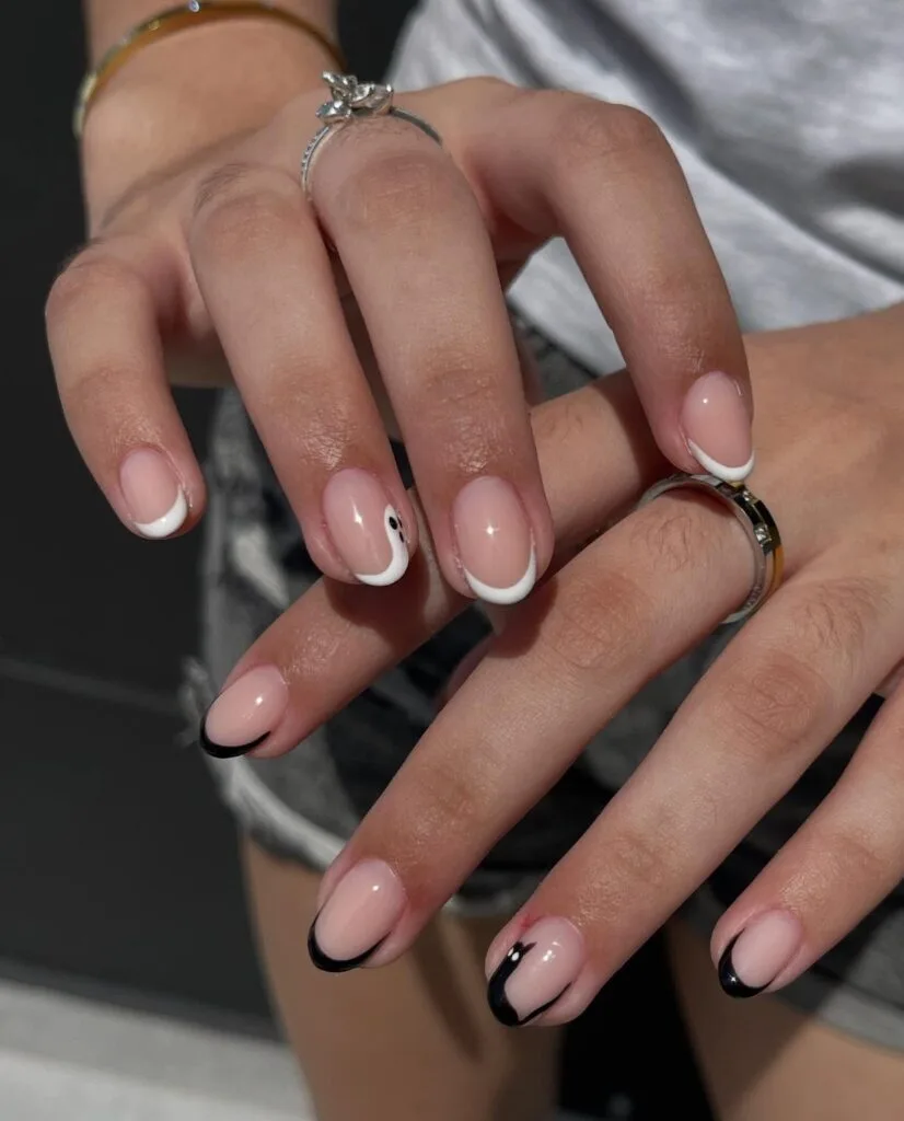 short Halloween nails with black and white micro French tips and a tiny ghost accent
