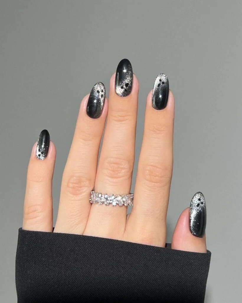 Black oval Halloween nails with silver glitter ghosts facing different directions and tiny black faces.