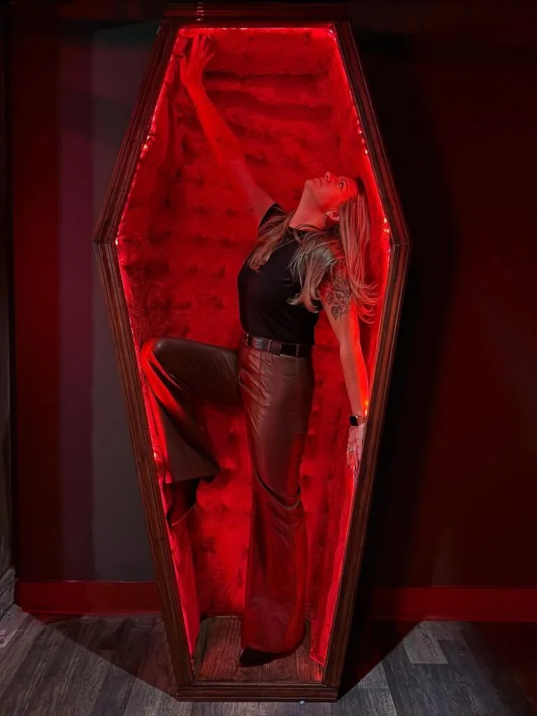 Red-lit coffin Halloween photo prop with a guest posing inside
