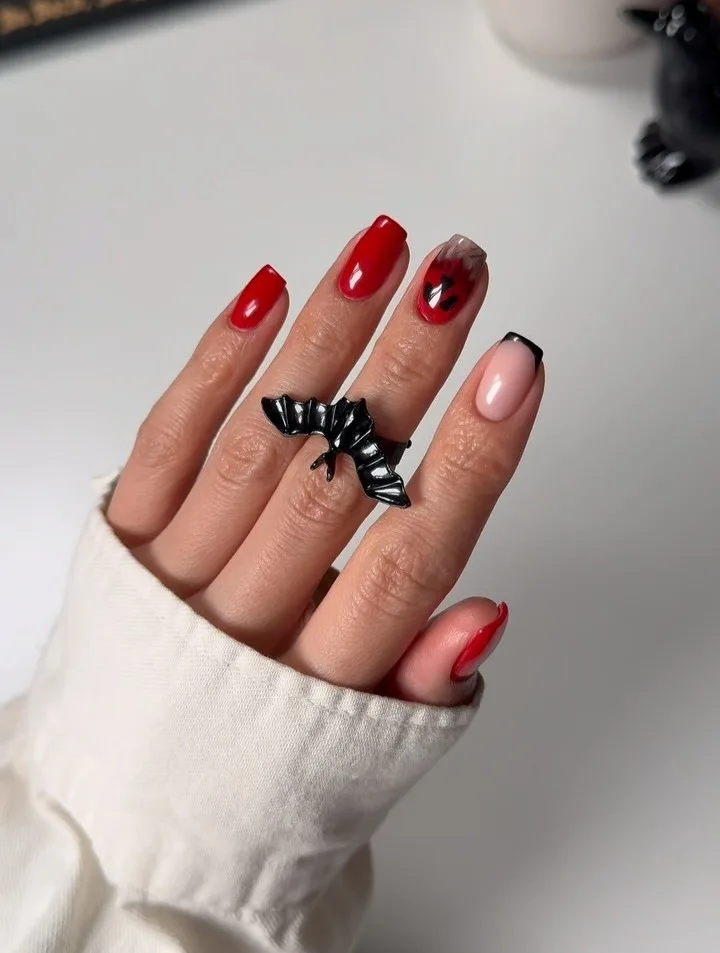 short red Halloween nails with a smoky gray accent featuring a red ghost and one black French tip