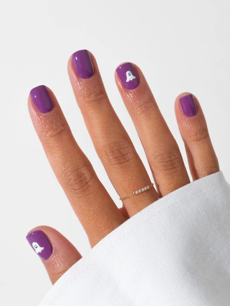 short spooky nails in glossy purple with small white ghost accents