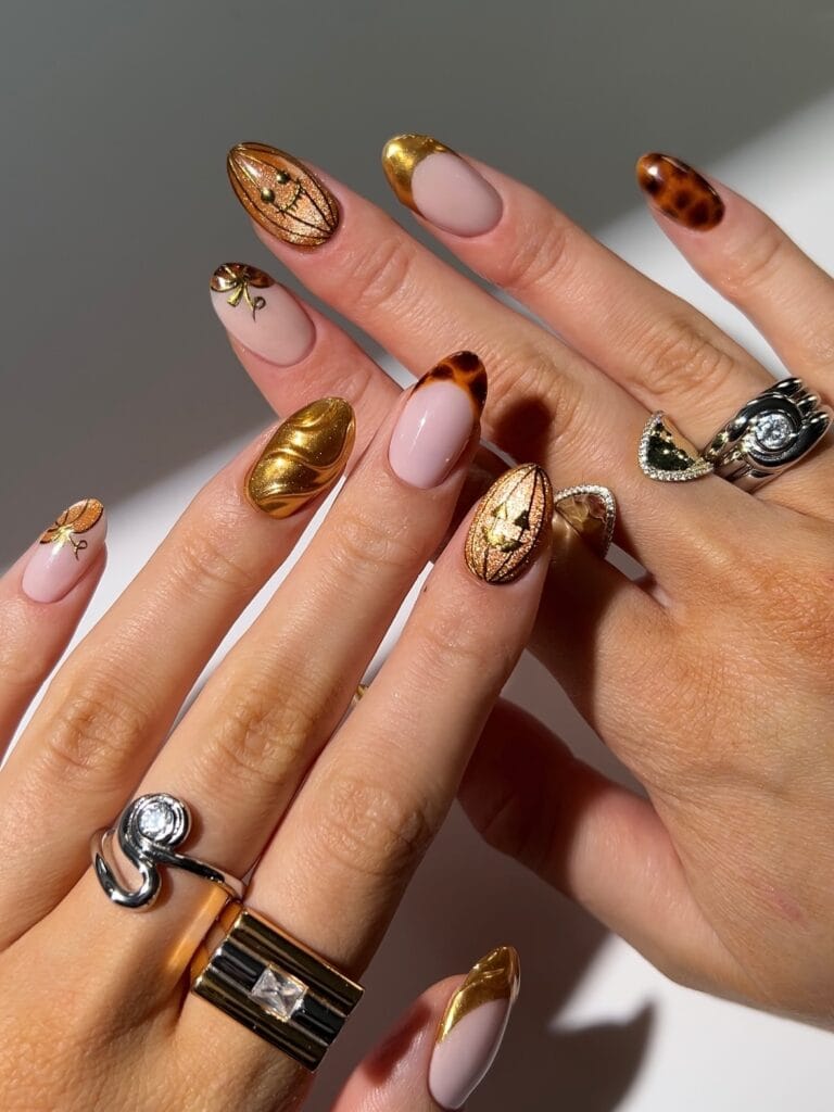October nails with gold chrome, tortoiseshell accents, nude bases, and amber nail art.
