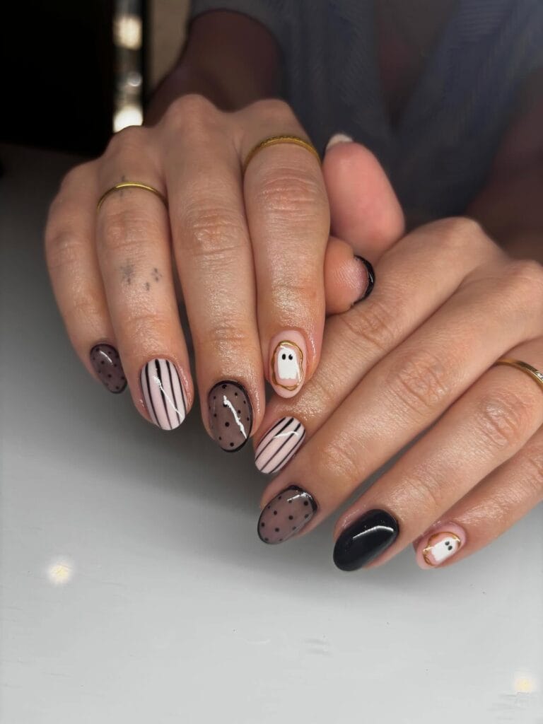 short Halloween nails with sheer black dotted accents, striped nail art, glossy black polish, and ghost details
