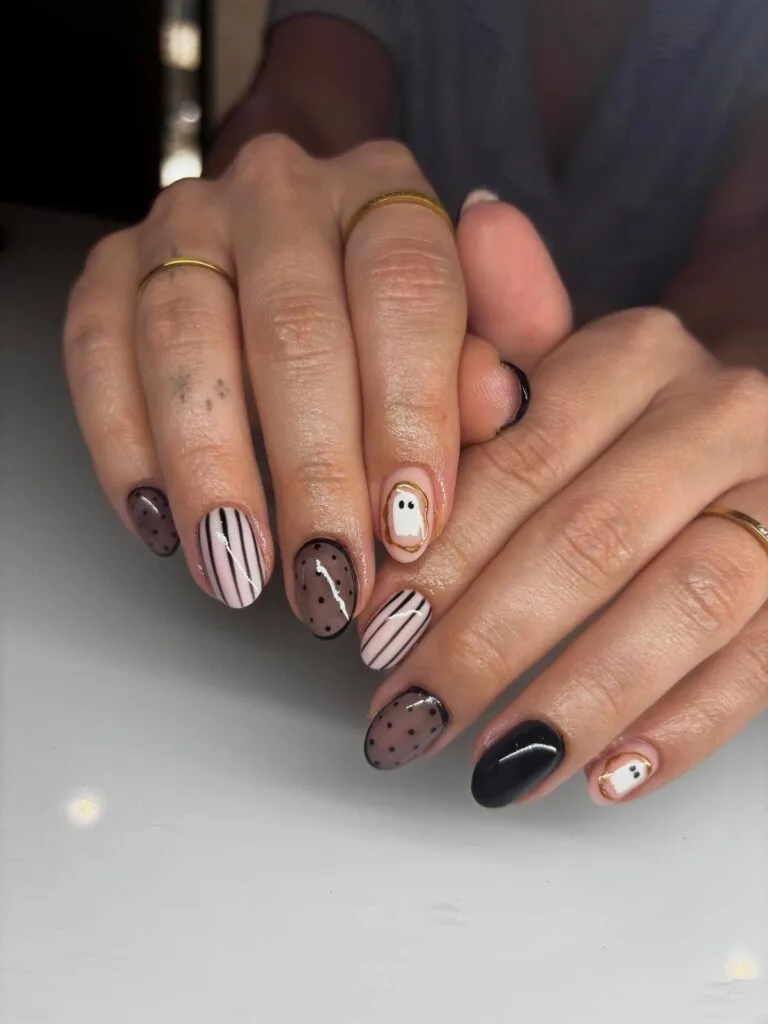 short Halloween nails with sheer black dotted accents, striped nail art, glossy black polish, and ghost details