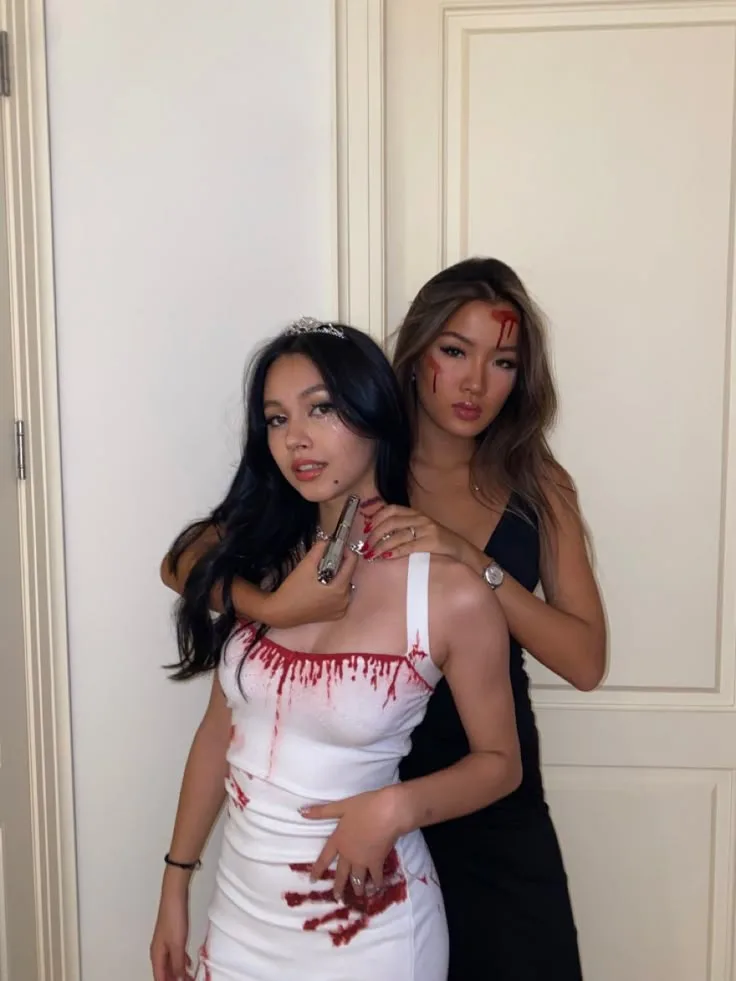 Best friend Halloween costumes with a blood-stained white bridal dress, tiara, black dress, and toy pistol.