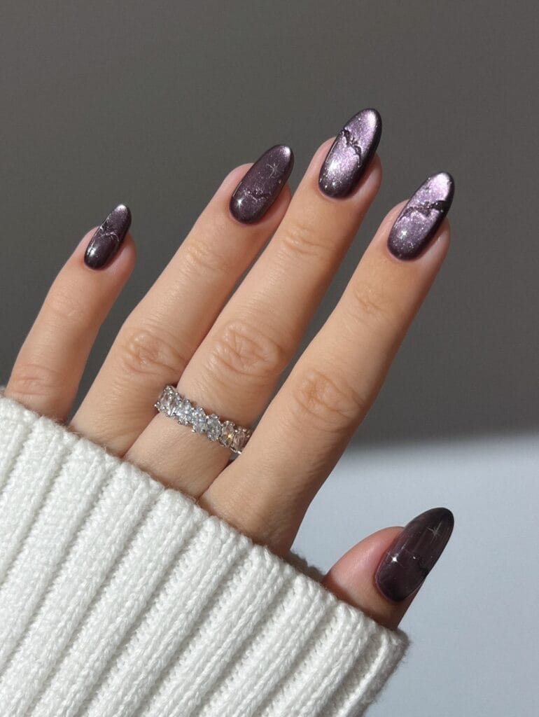 Autumn nails with smoky plum cat-eye polish, silver crackle detail, and glossy almond shapes.

