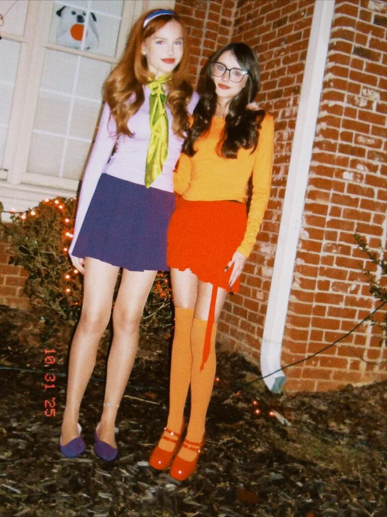 Daphne and Velma Halloween costumes for friends with purple separates, a green scarf, and an orange sweater