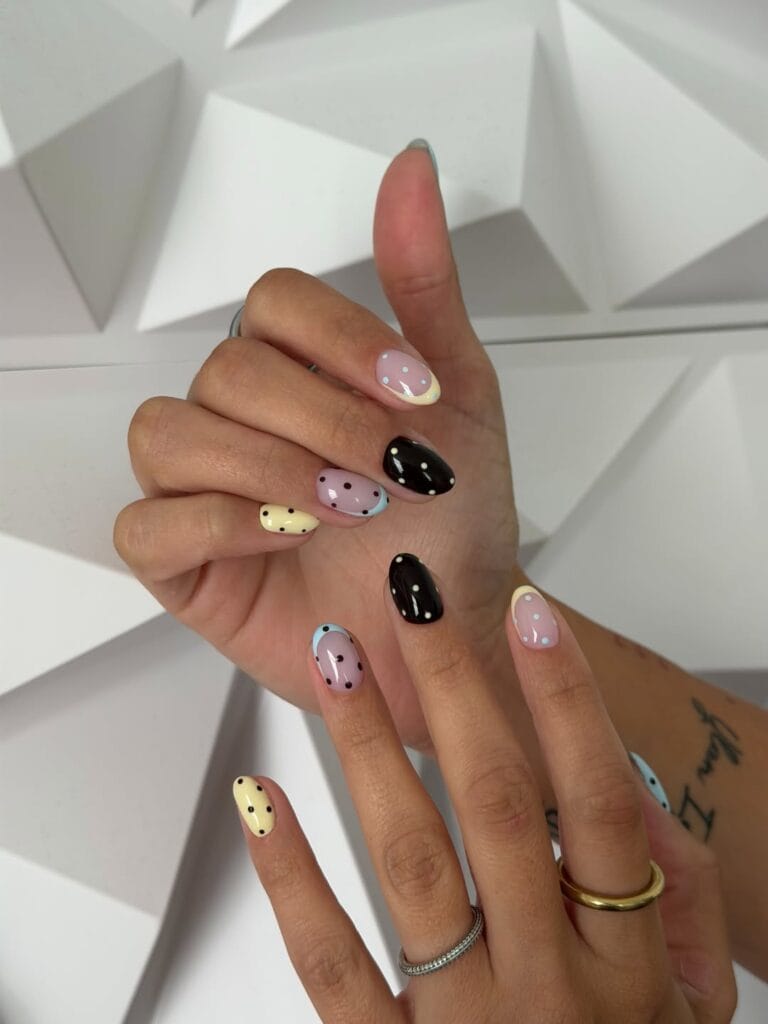 Fall polka dot nails with butter yellow and pale blue French tips, pink bases, and dark dotted accents.
