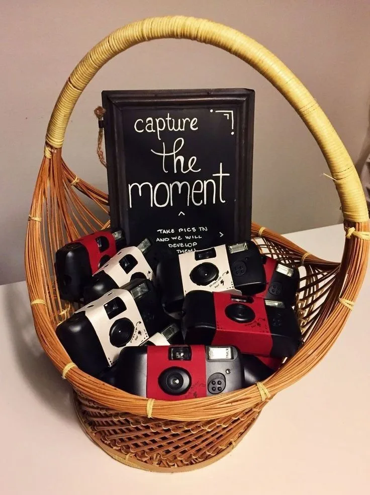Basket of disposable cameras with a "capture the moment" sign for Halloween party guests
