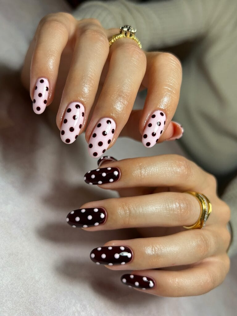 Oval fall polka dot nails with burgundy dots on pale pink on one hand and pale pink dots on burgundy on the other.
