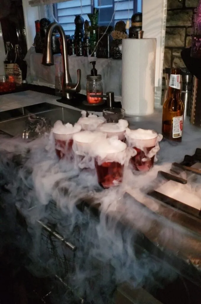 Halloween party drinks surrounded by dry ice fog on a kitchen counter

