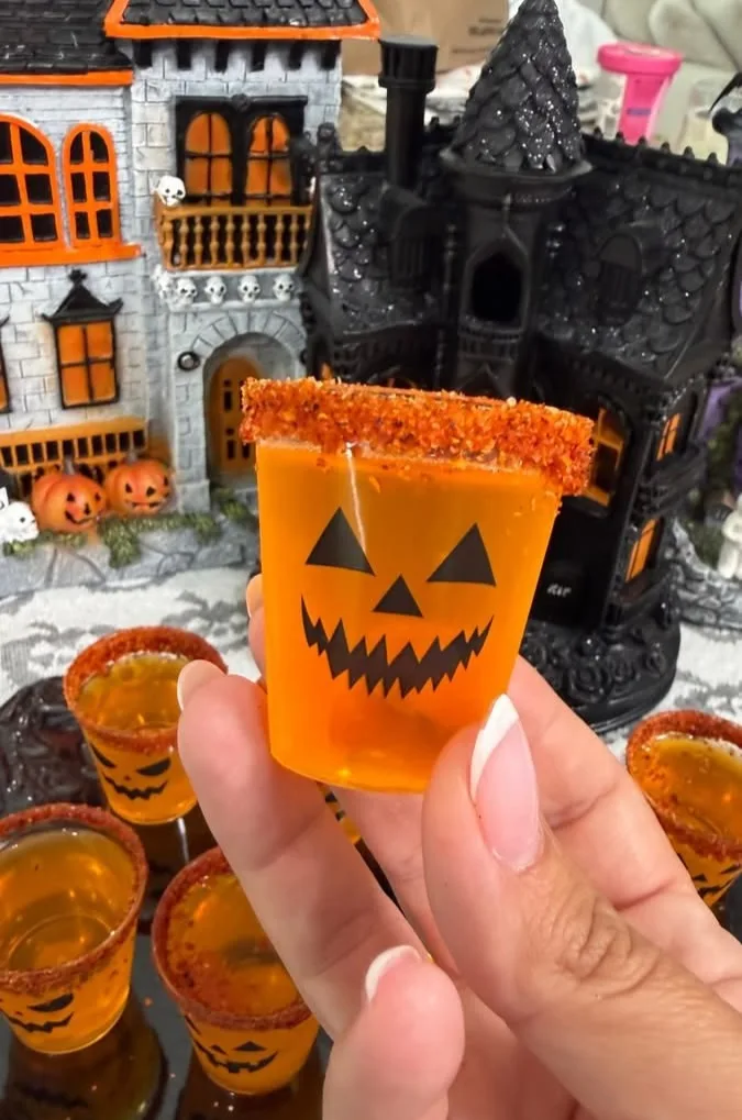 Orange Halloween shot cups with jack-o’-lantern faces and spiced rims
