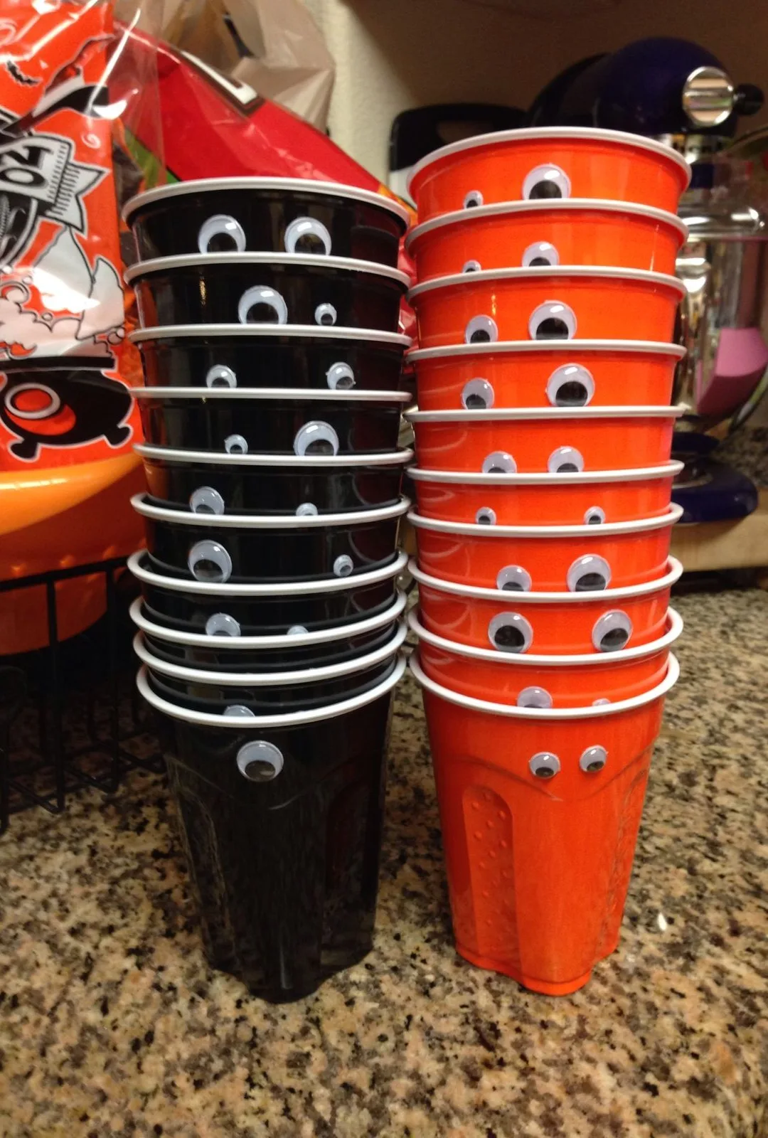 Black and orange Halloween party cups decorated with googly eyes
