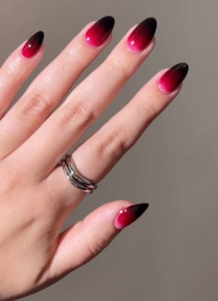 Glossy almond Halloween nails with bright red bases fading into nearly black tips.