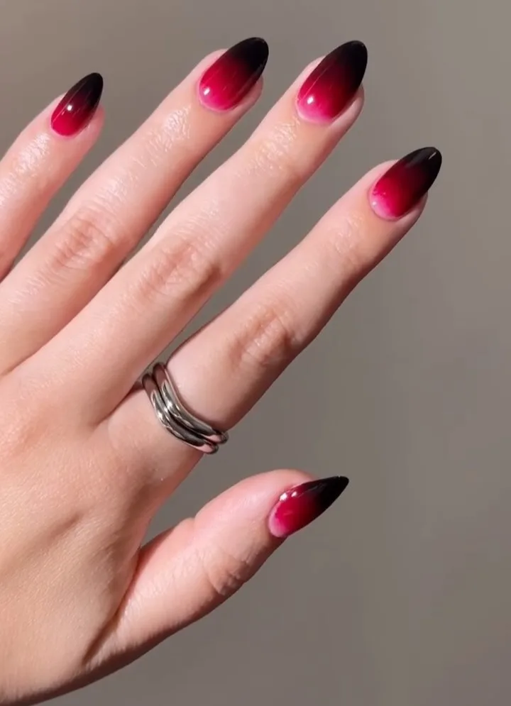 Glossy almond Halloween nails with bright red bases fading into nearly black tips.
