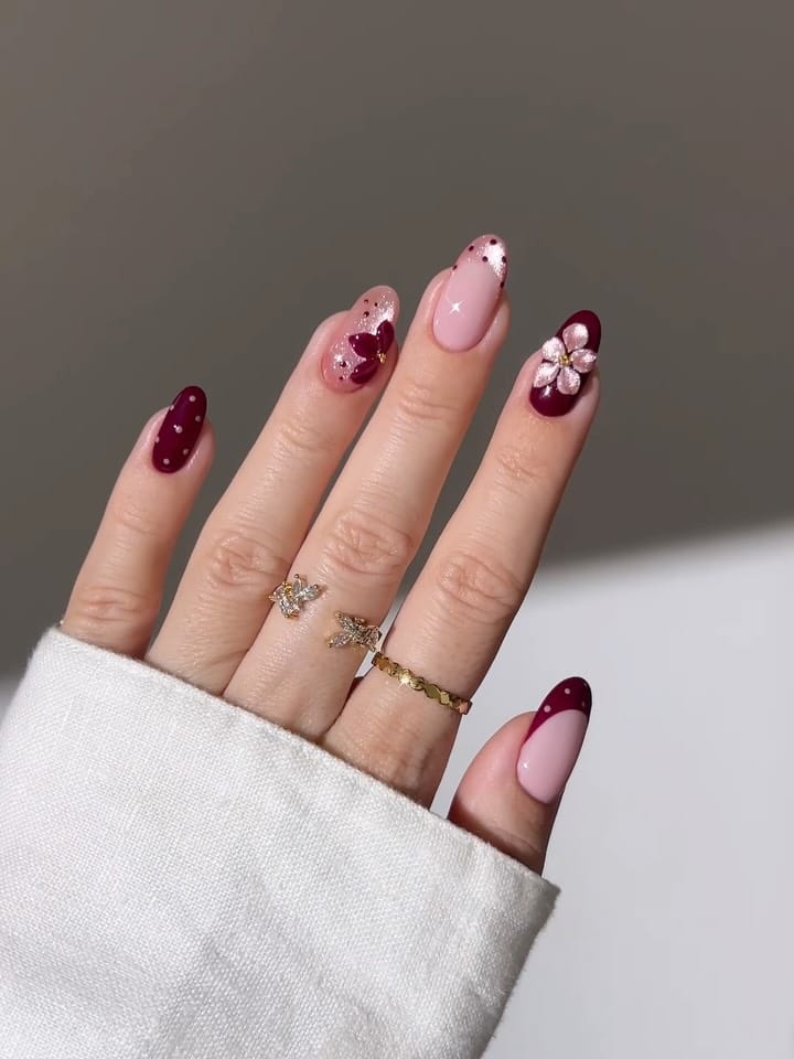 Pink and burgundy fall polka dot nails with shimmery French tips and raised flowers with gold centers.
