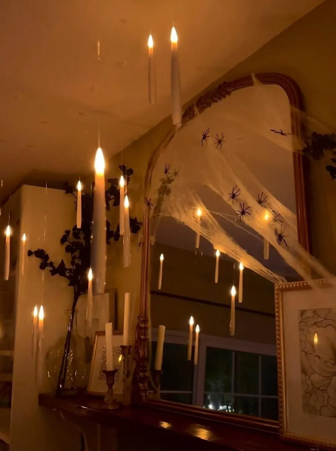 Halloween lighting with floating candles, spiderwebs, and black spiders around a large mirror
