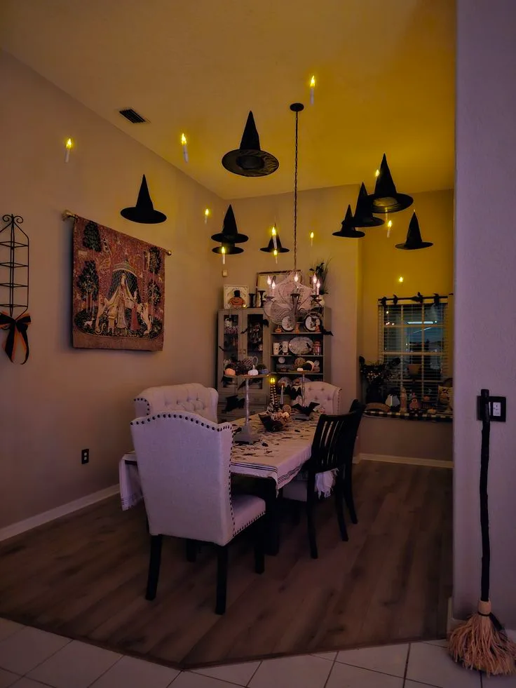 Halloween ceiling decor with hanging witch hats and floating candles over a dining room
