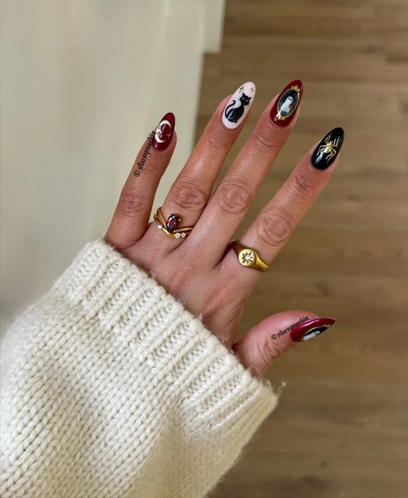 Burgundy, black, and pale pink Halloween nails with framed ghosts, a cat, and gold spider