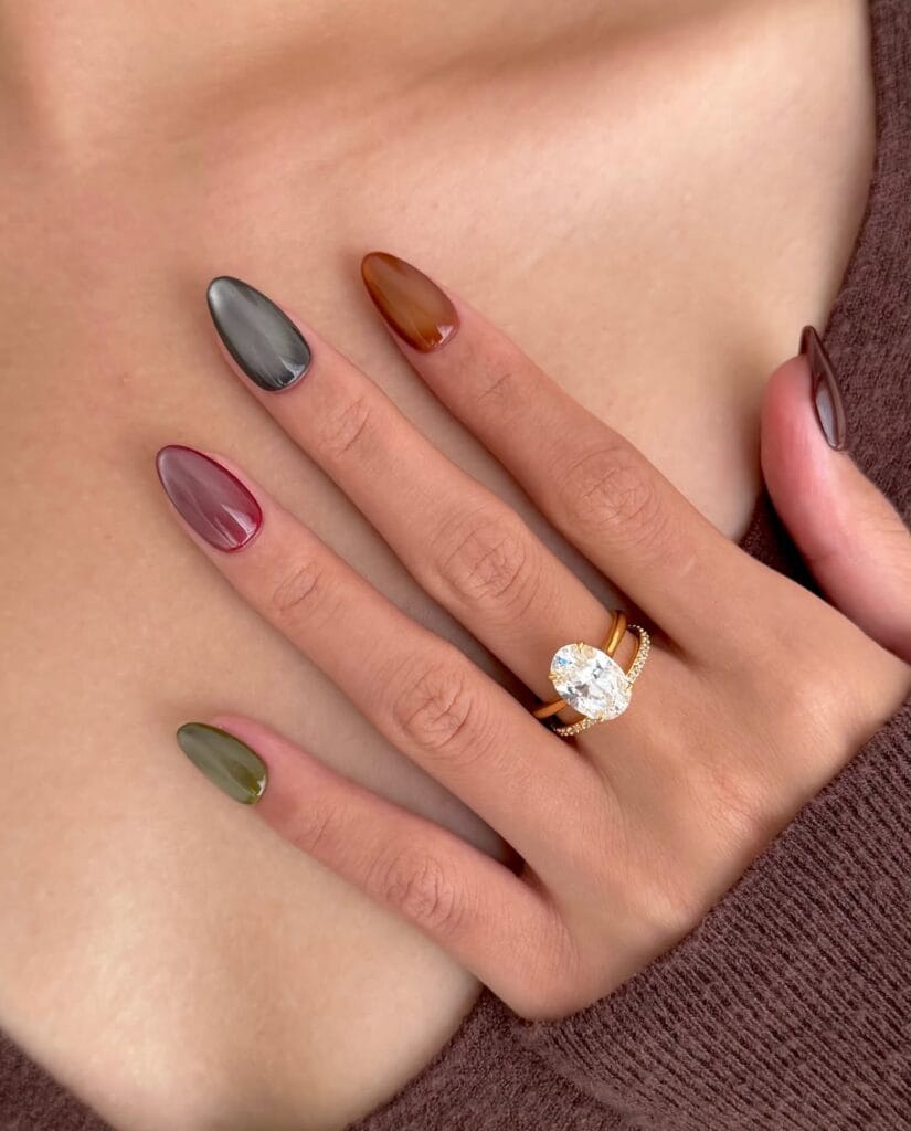 Cat-eye October nails in smoky gray, amber, mauve, olive, and burgundy with glossy almond shapes.

