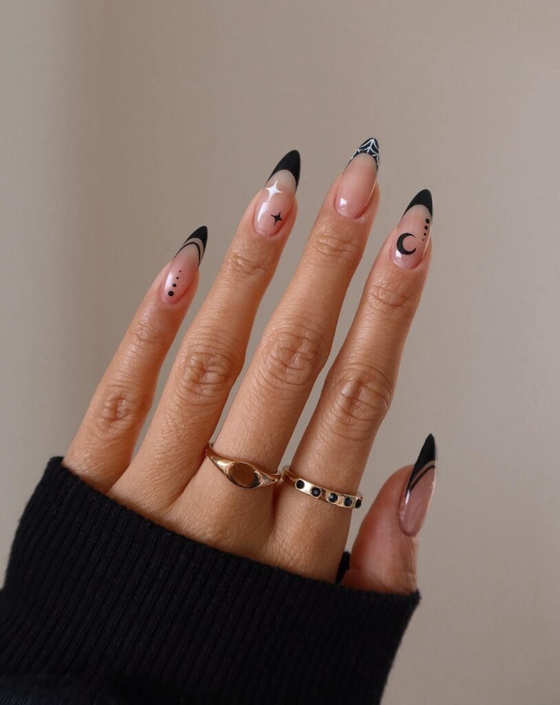 Witchy black French tips on nude almond nails with a crescent moon, stars, dotted trails, and a white web.