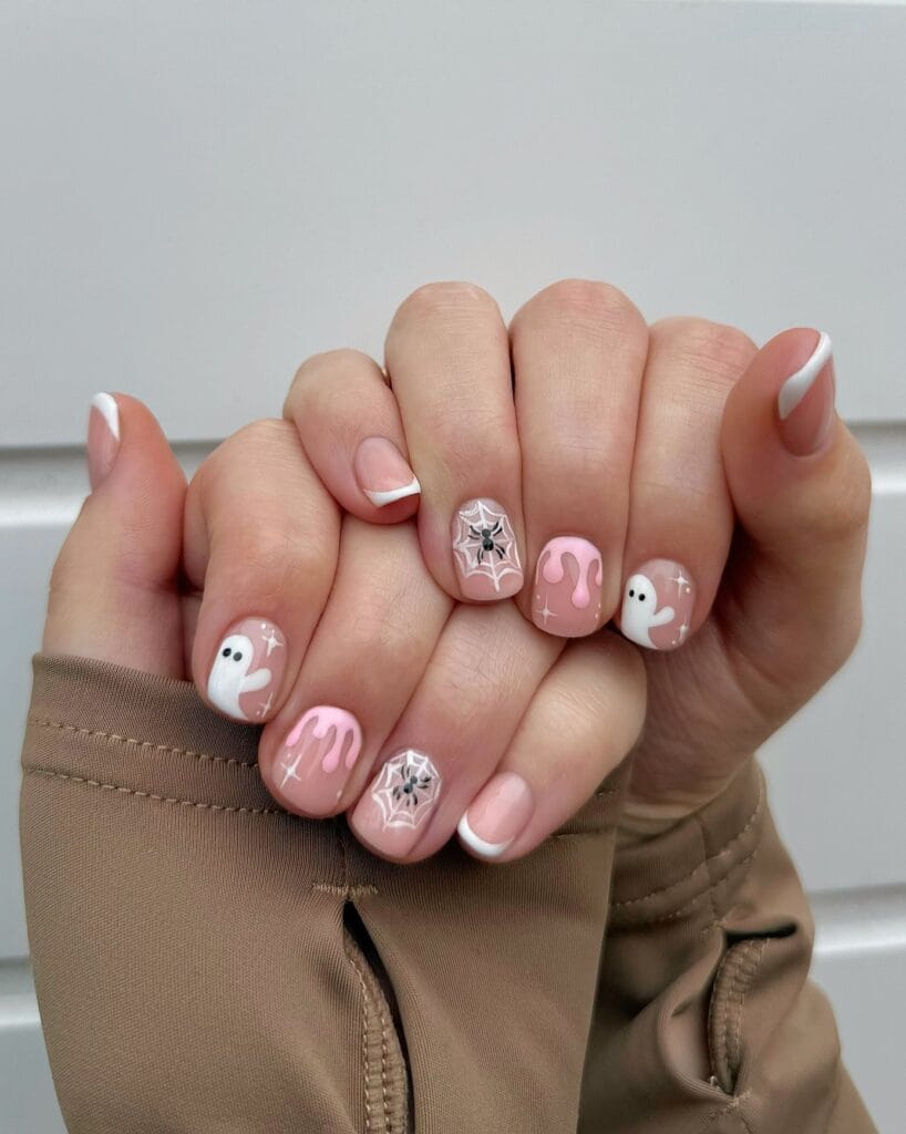 short Halloween nails with pink drip art, tiny ghosts, spiderweb accents, and white French tips
