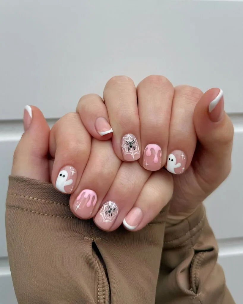 short Halloween nails with pink drip art, tiny ghosts, spiderweb accents, and white French tips