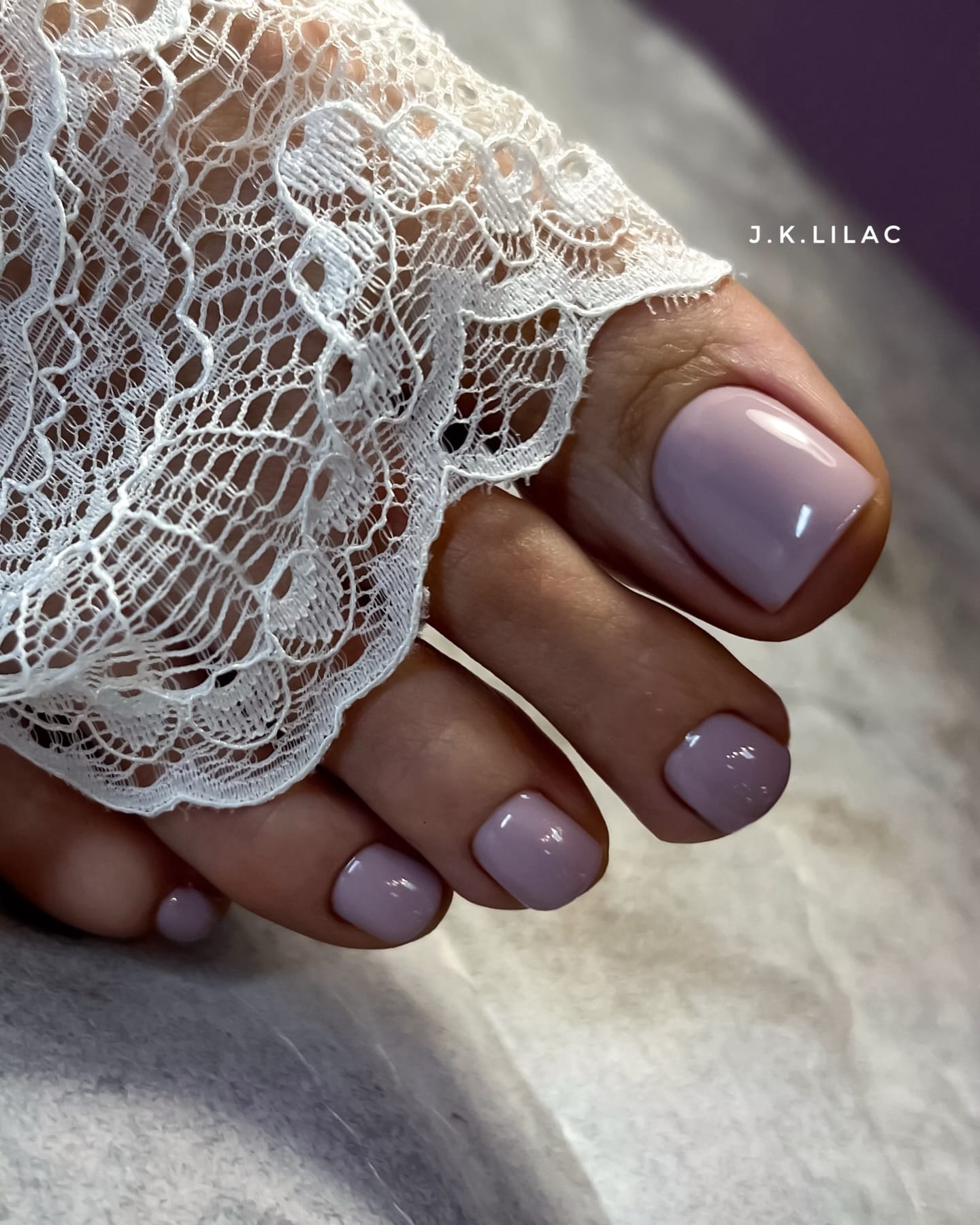 Glossy lavender toe nail color for fall beside white lace.