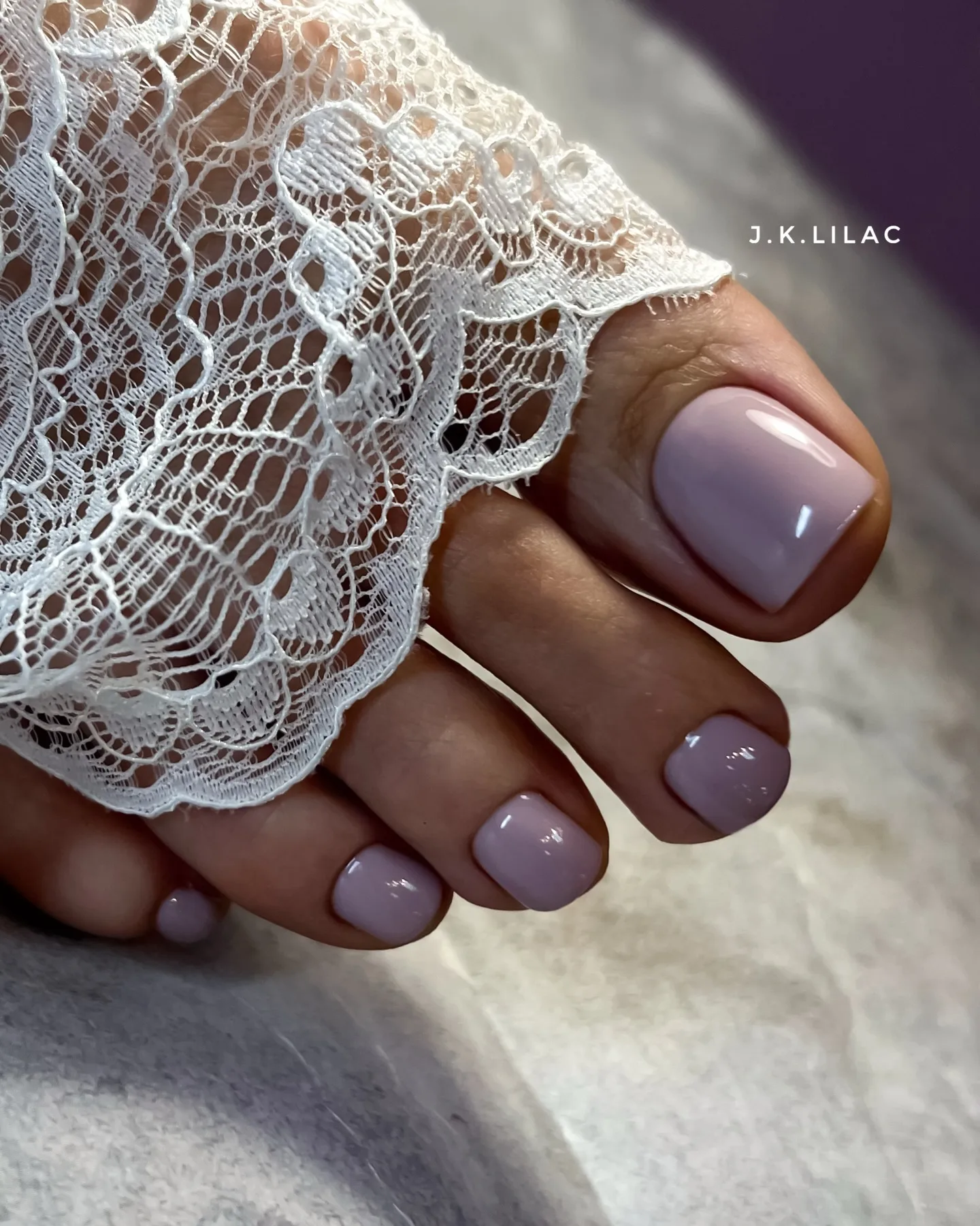 Glossy lavender toe nail color for fall beside white lace.
