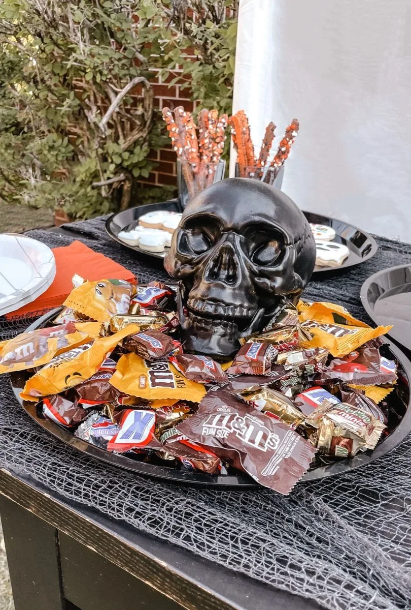Halloween candy display with assorted chocolate and orange candy around a black skull centerpiece

