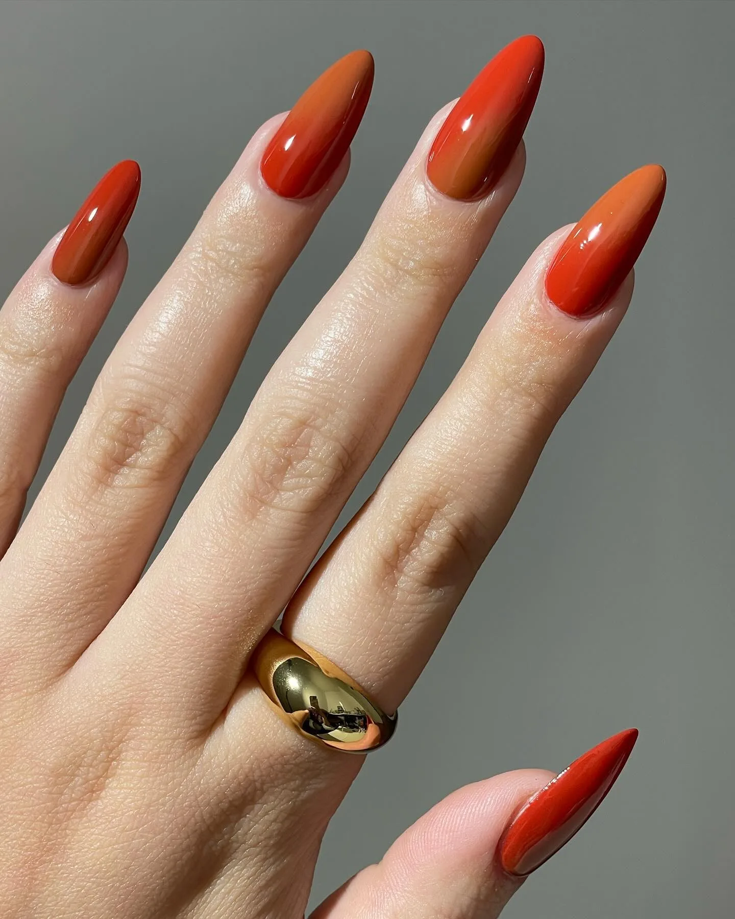Long almond November nail colors in a blended red-orange and burnt orange gradient with a glossy finish