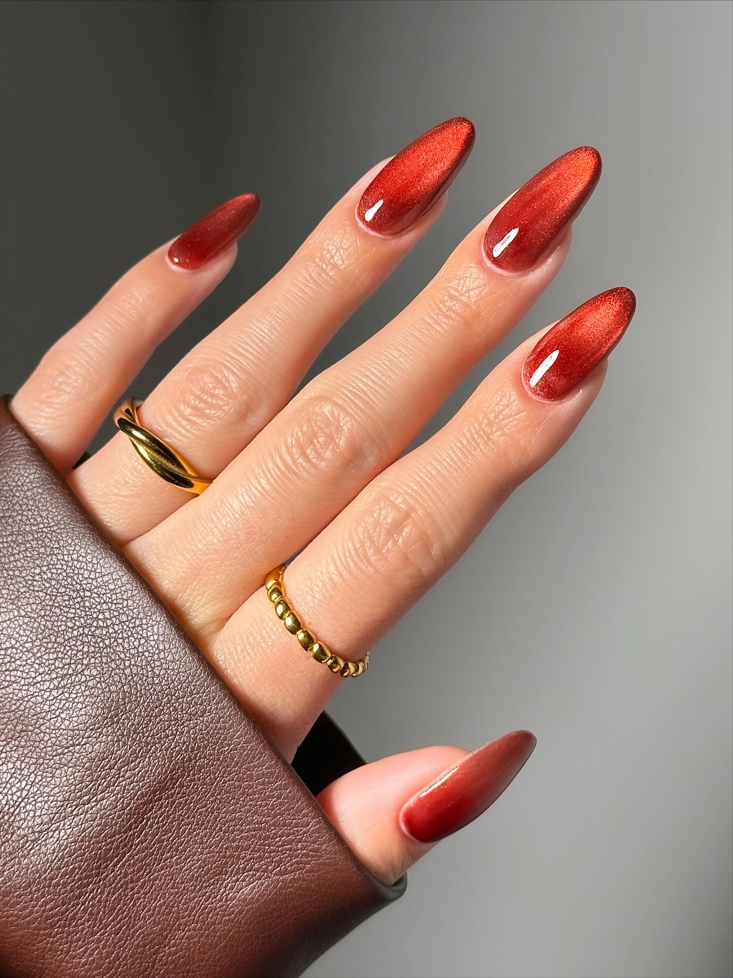 Almond November nail colors in rust red velvet cat-eye with a soft glowing shimmer
