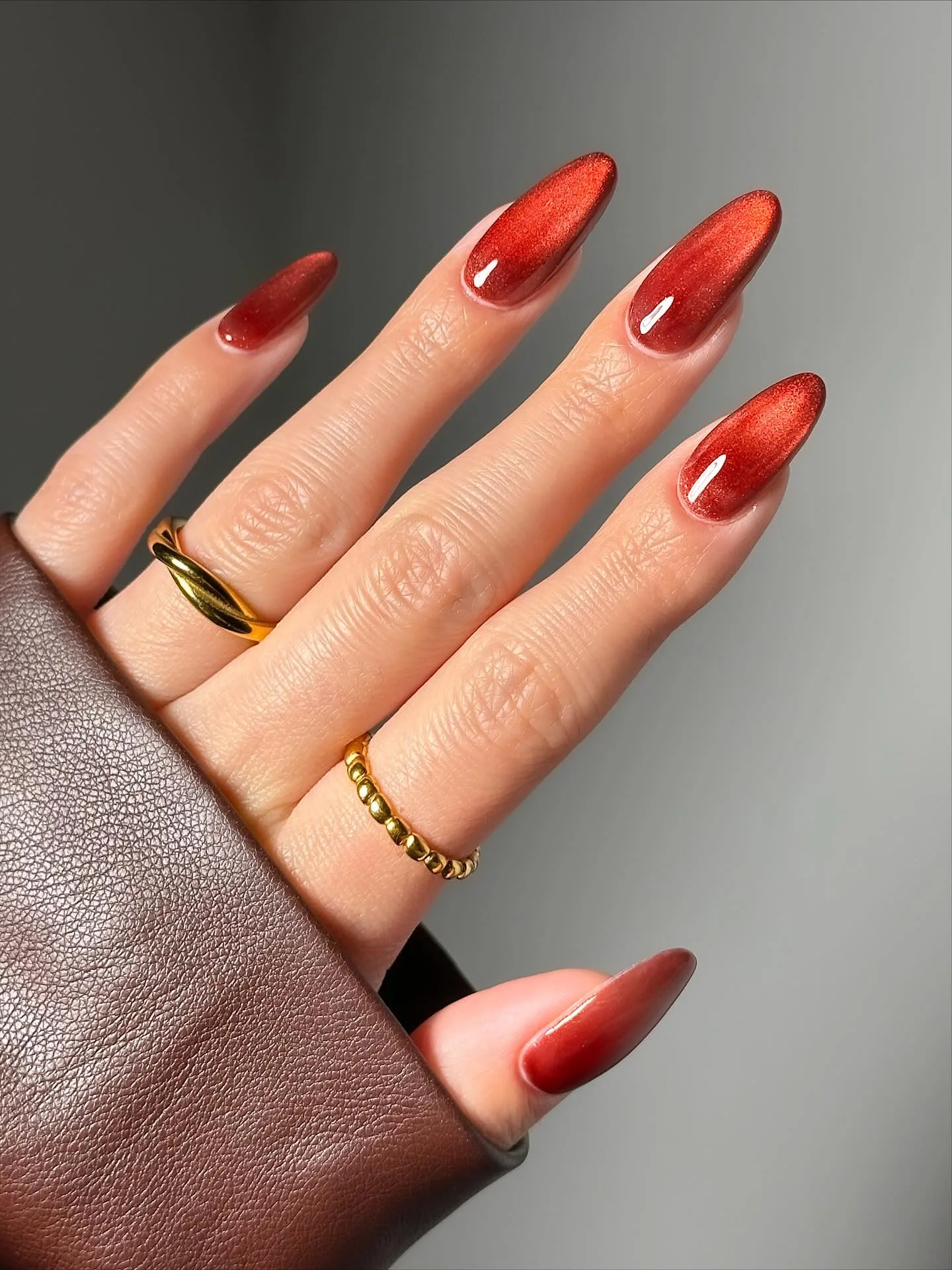Almond November nail colors in rust red velvet cat-eye with a soft glowing shimmer